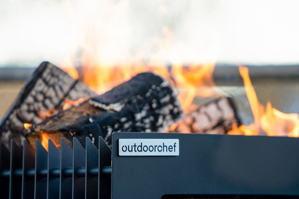 Firepit bålpanne med grillrist rustfritt stål svart - Outdoorchef i bruk med flammer